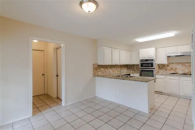 a kitchen with granite countertop a sink and white cabinets