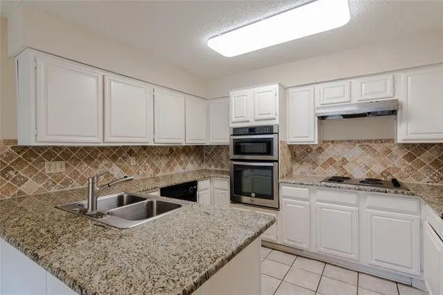 a kitchen with granite countertop white cabinets and stainless steel appliances