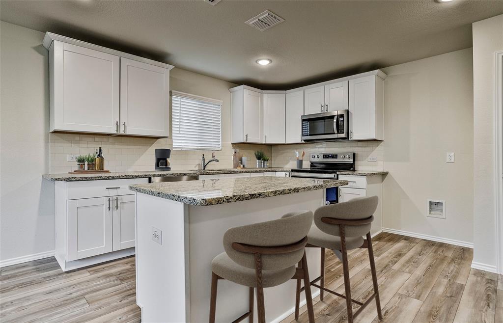 14057 Ladbroke Street Pilot Point, TX 76258 - Photo 7 of 11 a kitchen with a stove a sink and a microwave
