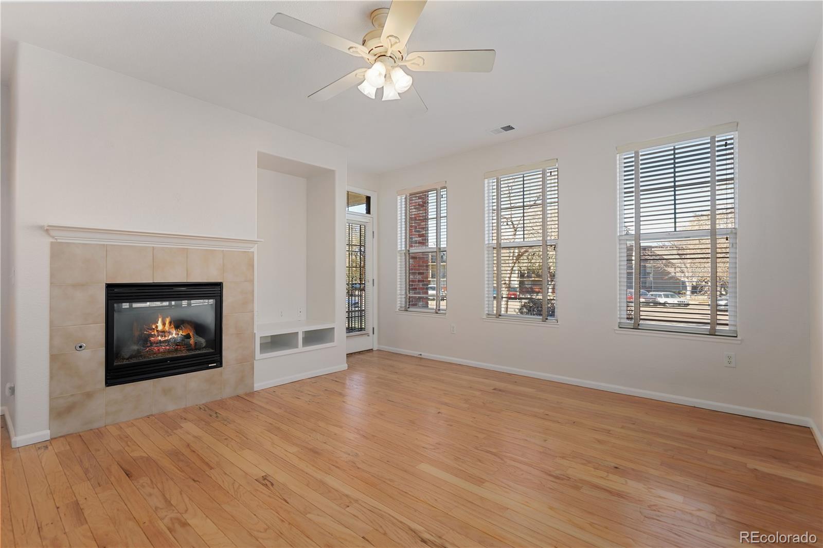 an empty room with windows fireplace and fan