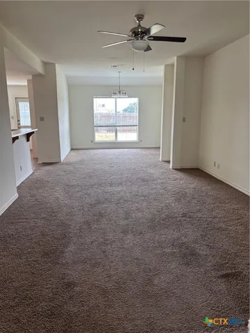 en empty room with windows and ceiling fan