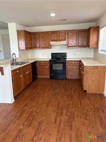a large kitchen with stainless steel appliances granite countertop a stove a sink dishwasher and a microwave oven with wooden floor