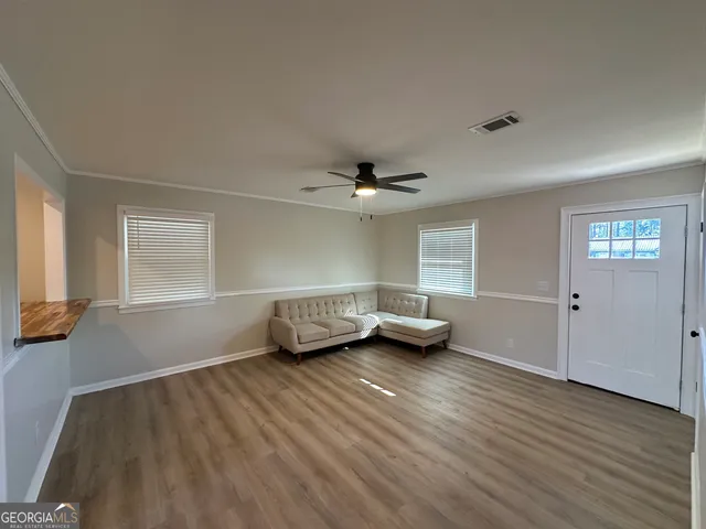 an empty room with windows and ceiling fan