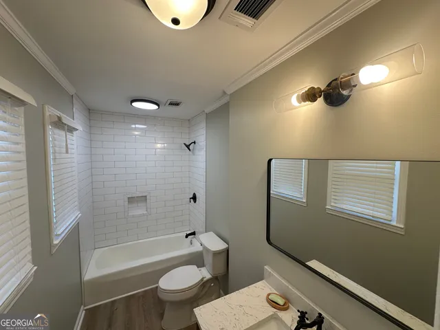a bathroom with a granite countertop bathtub shower sink vanity and toilet