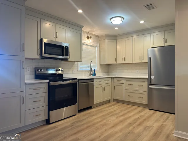 a kitchen with granite countertop a refrigerator stove top oven and sink