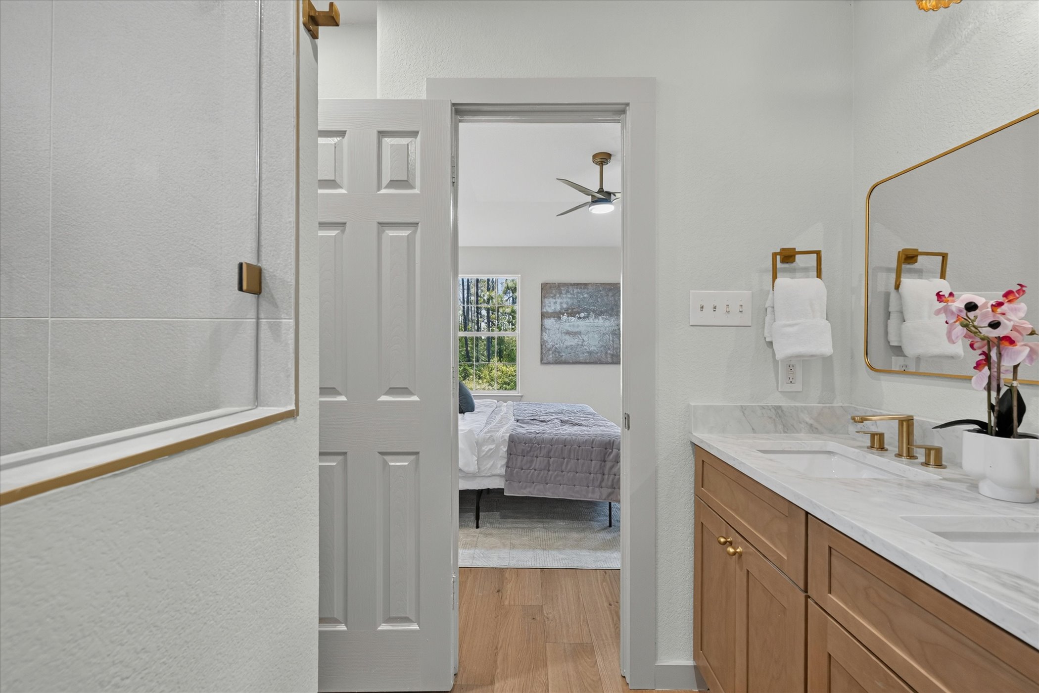 258 Pine View Loop Bastrop, TX 78602 - Photo 32 of 40 Marble countertops and light wood cabinetry adorn this well-appointed primary bathroom, with a glimpse into the adjacent bedroom.