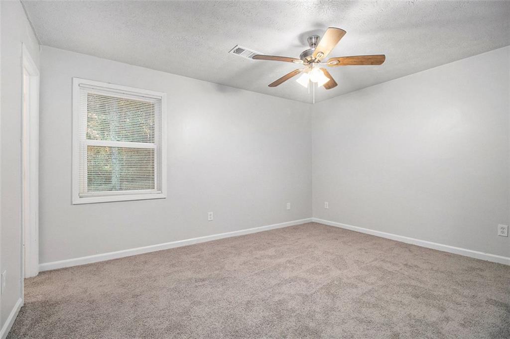 1748 Charmeth Road Lithonia, GA 30058 - Photo 11 of 32 an empty room with a window and a fan