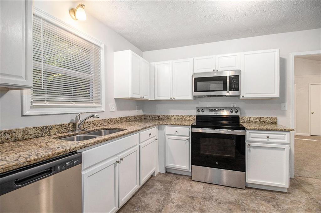 1748 Charmeth Road Lithonia, GA 30058 - Photo 5 of 32 a kitchen with granite countertop a sink stove and microwave