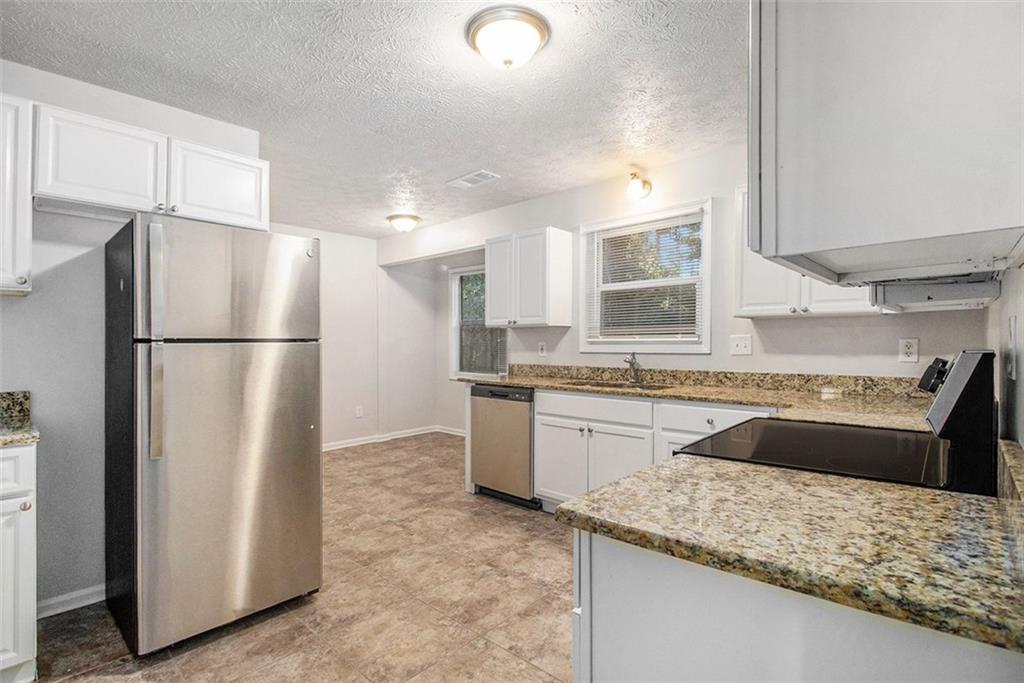 1748 Charmeth Road Lithonia, GA 30058 - Photo 6 of 32 a kitchen with stainless steel appliances granite countertop a refrigerator and a sink