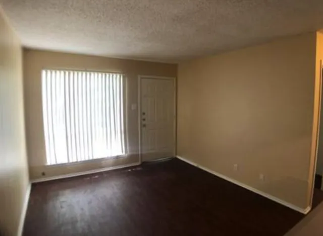 an empty room with wooden floor and windows with curtains view