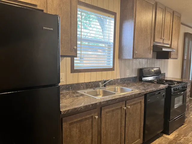 a kitchen with granite countertop sink stove and cabinets