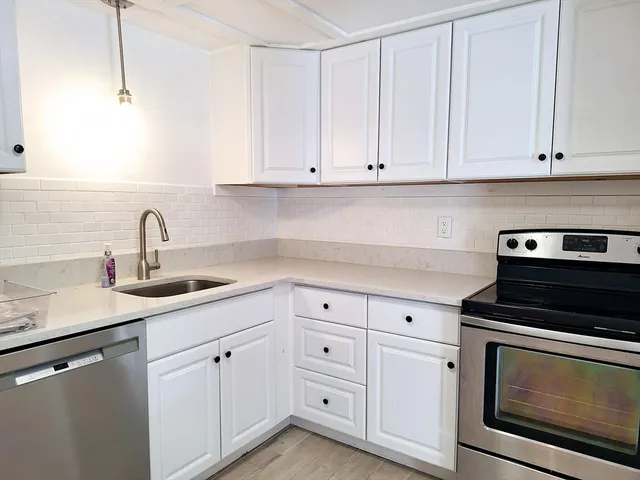 a kitchen with white cabinets and sink