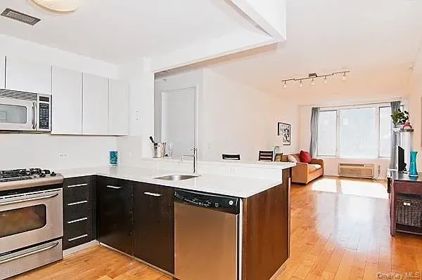 a kitchen with stainless steel appliances a sink dishwasher stove refrigerator and microwave with wooden floor