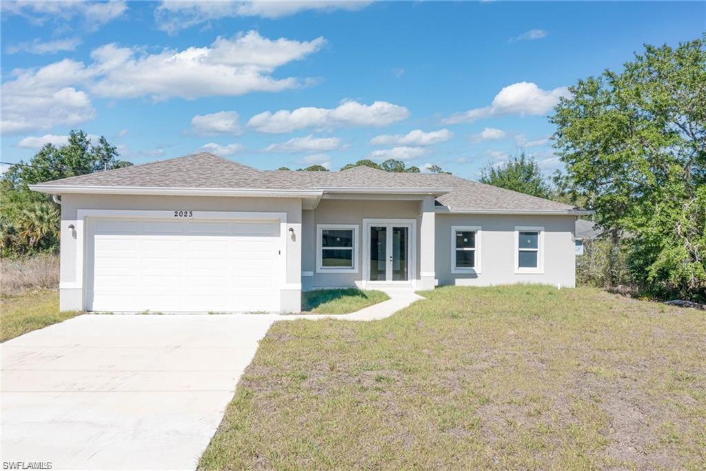 2023 Robert Avenue Alva, FL 33920 - Photo 1 of 8 View of front of house with french doors, a front lawn, stucco siding, a garage, and driveway