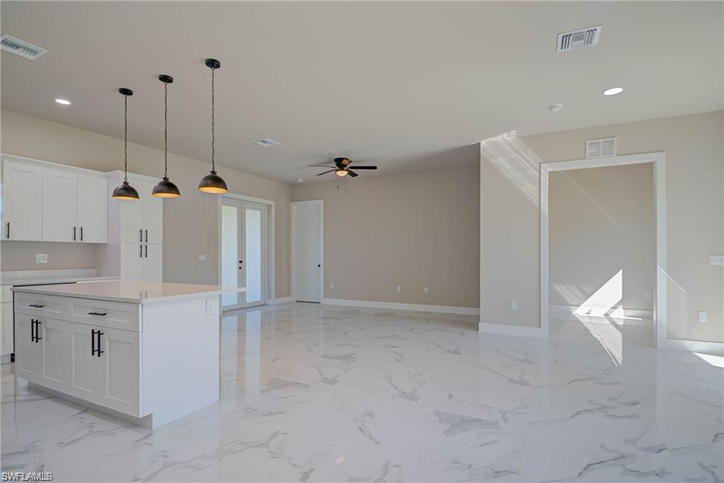 2023 Robert Avenue Alva, FL 33920 - Photo 3 of 8 Kitchen featuring recessed lighting, hanging light fixtures, white cabinets, a center island, and light marble finish flooring
