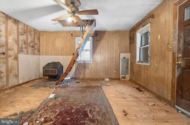 a view of a livingroom with a staircase a ceiling fan and window