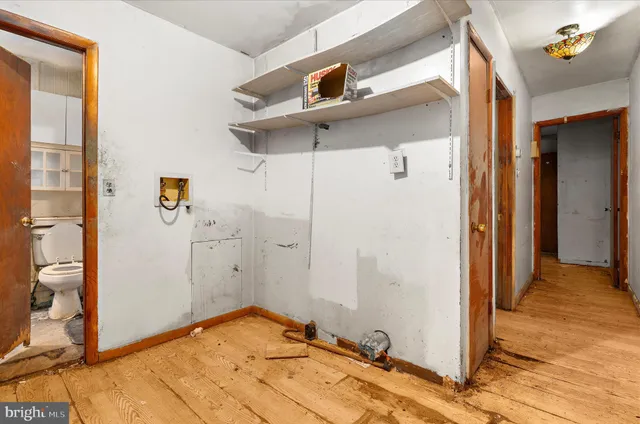 a view of a hallway with wooden floor and a bathroom