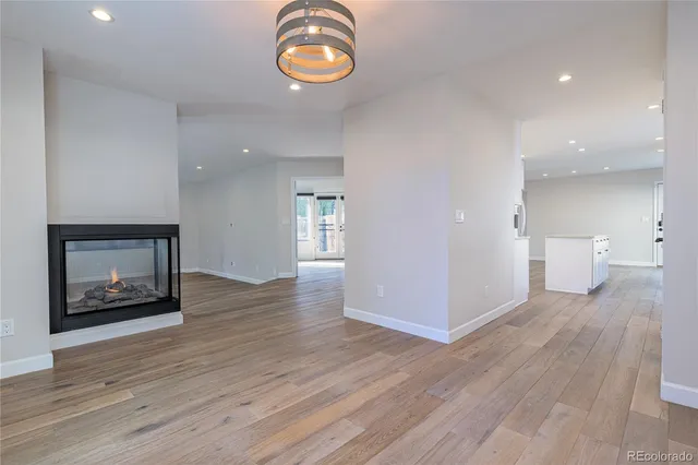 an empty room with wooden floor a fireplace and windows