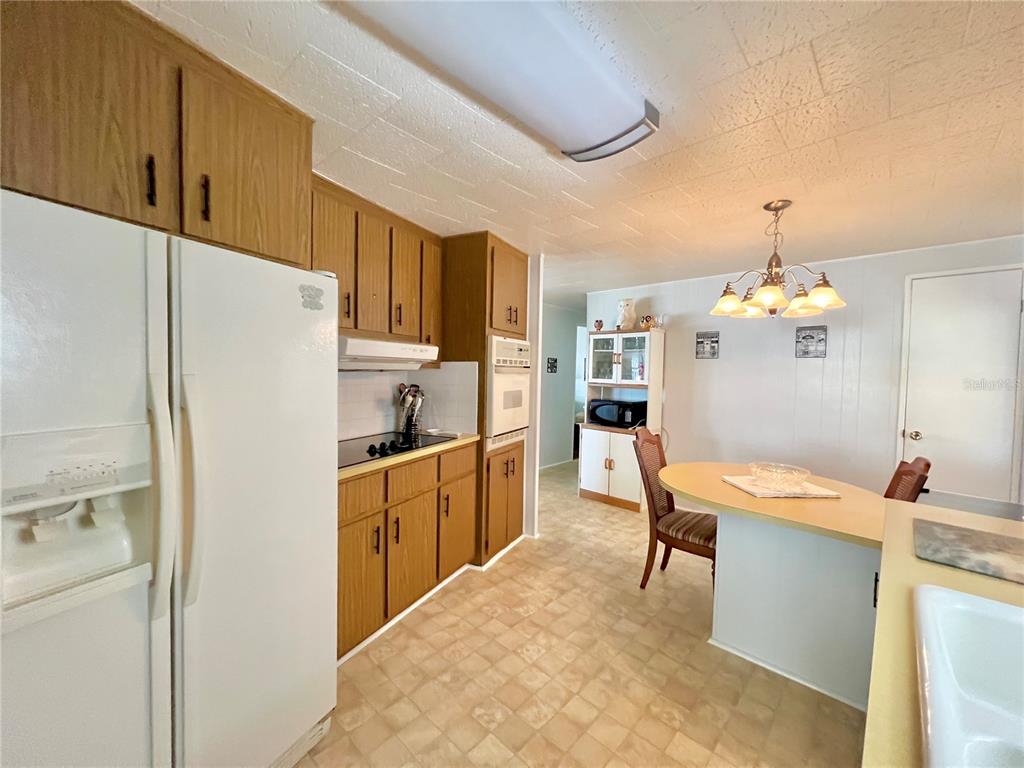 1100 South Belcher Road, Unit 719 Largo, FL 33771 - Photo 29 of 60 a kitchen with stainless steel appliances granite countertop a refrigerator a sink dishwasher a dining table and chairs with wooden floor