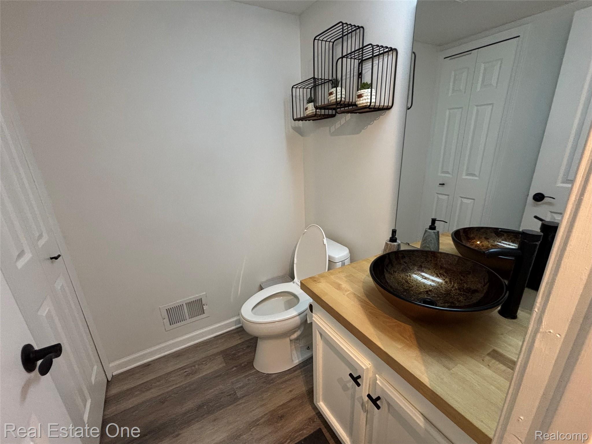 66 Meadow Wood Drive Rochester, MI 48307 - Photo 18 of 20 Bathroom vanity with two vessel sinks, a wood-finish countertop, and white cabinetry