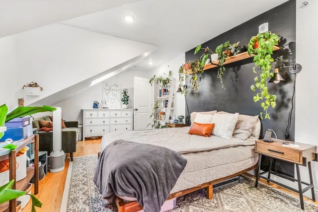 a bedroom with a bed a potted plant and a bookshelf