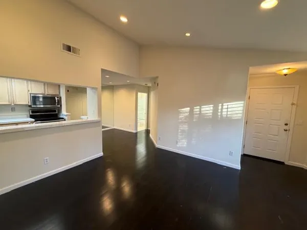 a view of a kitchen with refrigerator and wooden floor