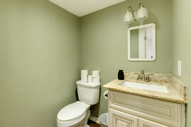 a bathroom with a granite countertop toilet sink and mirror
