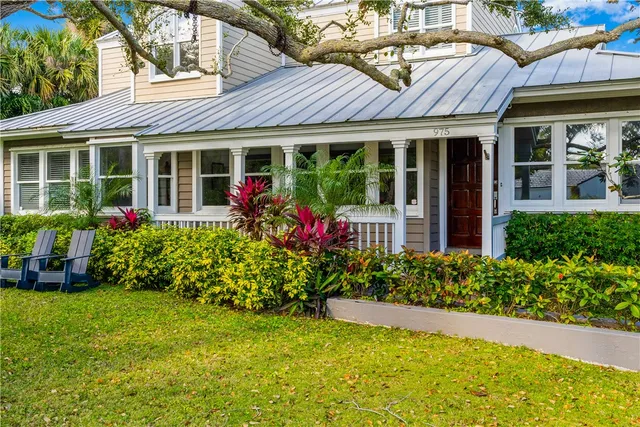 a front view of a house with a yard with plants and seating space