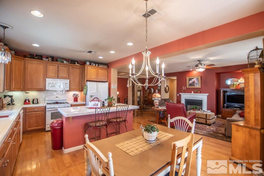 10655 Cedar Bend Court Reno, NV 89521 - Photo 3 of 16 a kitchen with stainless steel appliances kitchen island granite countertop a dining table chairs refrigerator sink and stove
