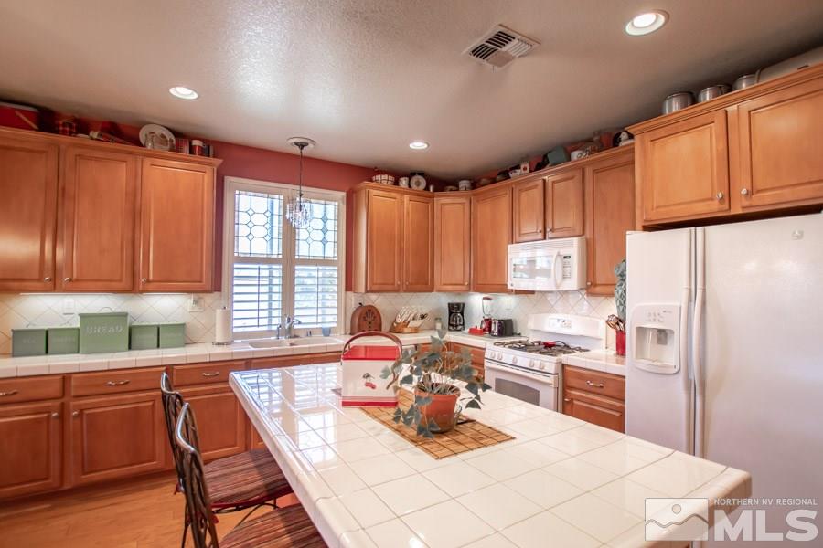 10655 Cedar Bend Court Reno, NV 89521 - Photo 6 of 16 a kitchen with a refrigerator a sink dishwasher with a dining table and chairs
