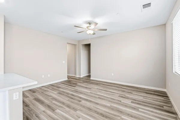 a view of an empty room with chandelier fan and a window