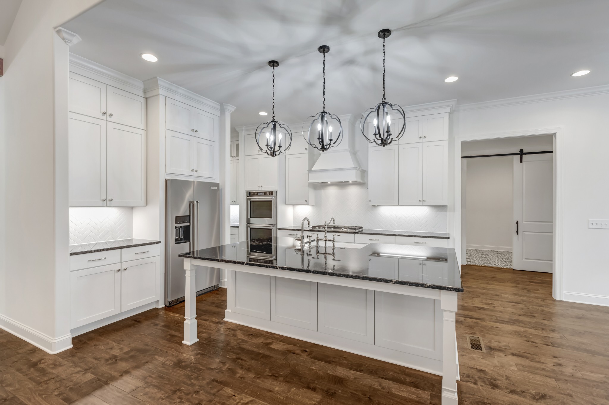 7483 Liberty Road Fairview, TN 37062 - Photo 28 of 65 a kitchen with stainless steel appliances kitchen island granite countertop a refrigerator a stove and white cabinets with wooden floor