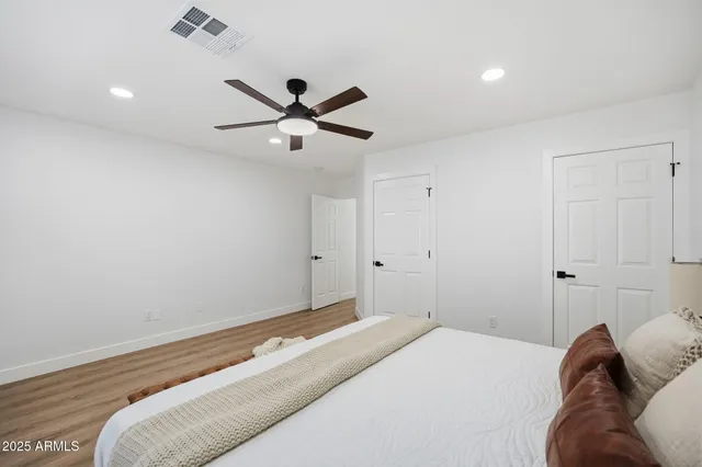 an empty room with wooden floor fan and windows