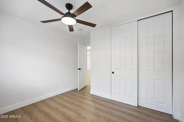 an empty room with wooden floor closet and windows