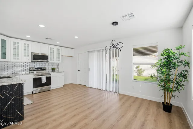 a kitchen with stainless steel appliances granite countertop a stove top oven a sink dishwasher and a refrigerator with wooden floor