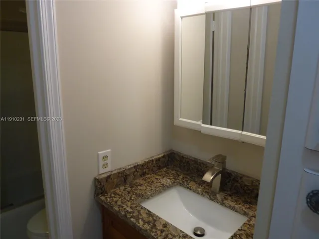 a bathroom with a granite countertop toilet and a sink