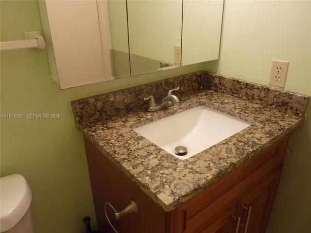 a bathroom with a granite countertop sink and a toilet