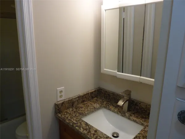 a bathroom with a granite countertop sink and a mirror