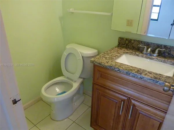 a bathroom with a granite countertop sink and a toilet