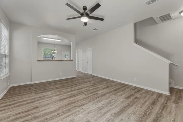 a view of empty room with wooden floor and fan