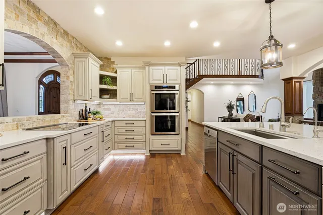 a large kitchen with stainless steel appliances and wooden floor