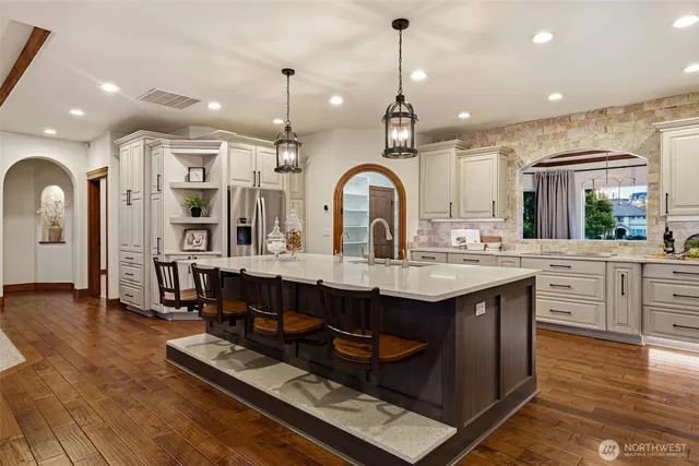 a kitchen with stainless steel appliances granite countertop a sink a stove and a wooden floors