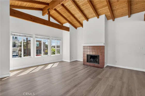 a view of an empty room with wooden floor fireplace and a window