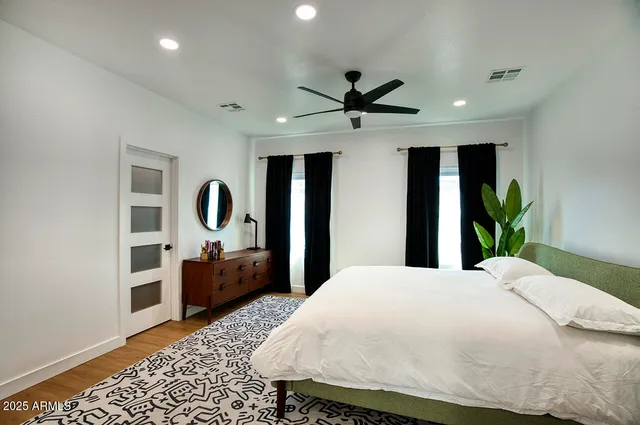 a bedroom with a bed a dresser and potted plant