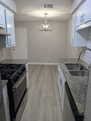 a kitchen with granite countertop a sink stove and refrigerator