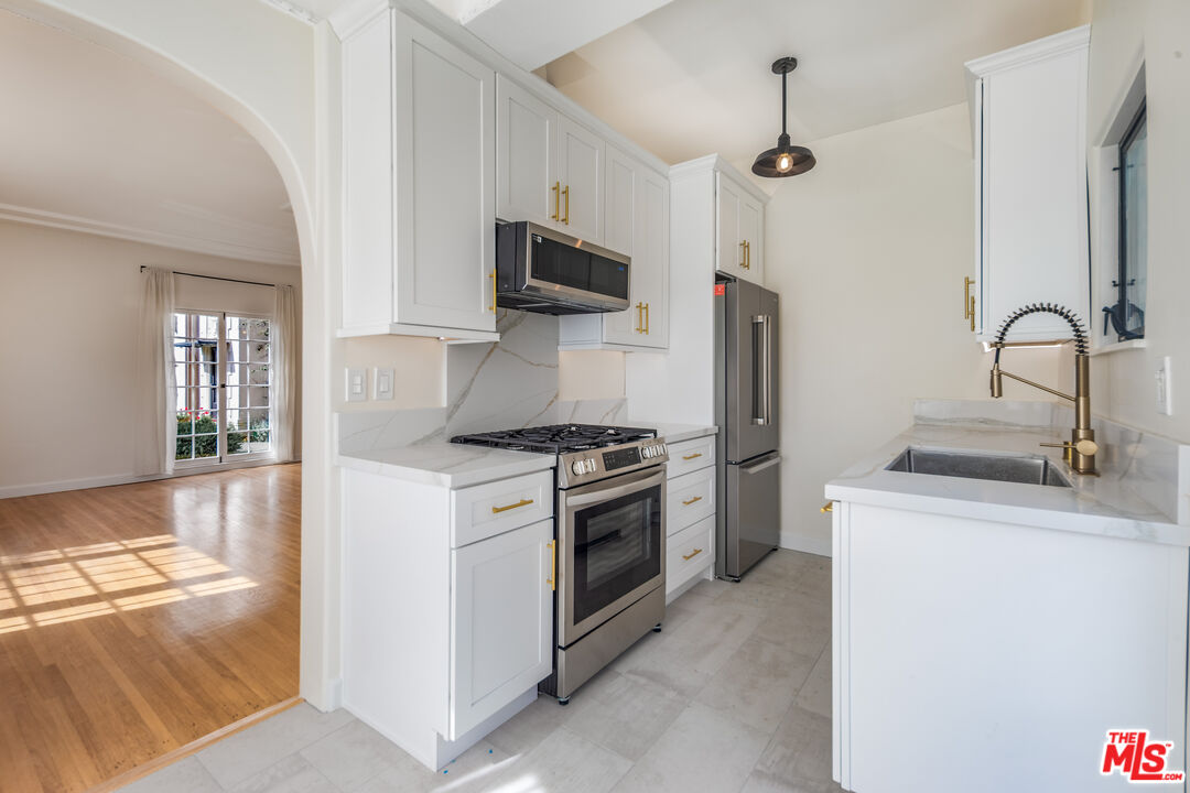 152 South Roxbury Drive, Unit 6 Beverly Hills, CA 90212 - Photo 8 of 51 a kitchen with stainless steel appliances granite countertop a sink and a stove top oven with wooden floor