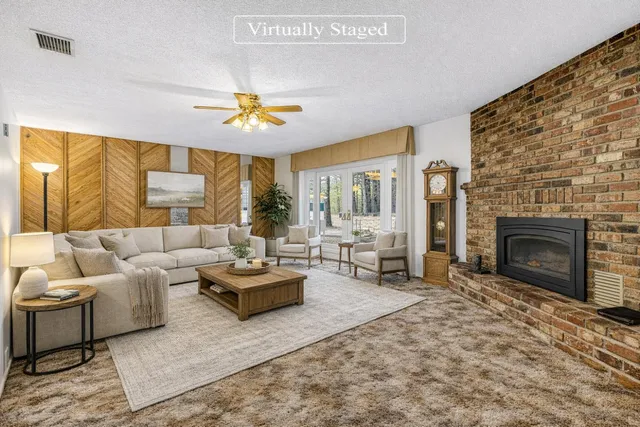 a living room with a fireplace furniture and a ceiling fan
