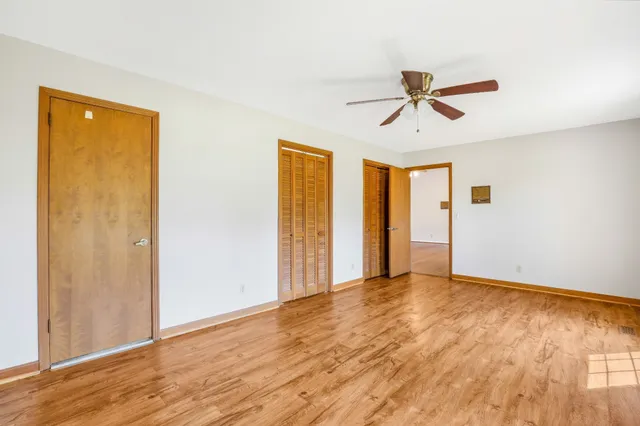 a view of empty room with wooden floor and ceiling fan