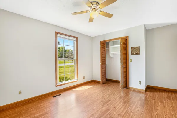a view of an empty room with window and wooden floor