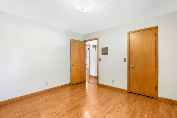 a view of an empty room with wooden floor and closet